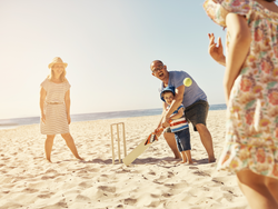 Australian family playing cricket on the beach.