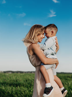 Mum and son in the sun on a green field hugging.