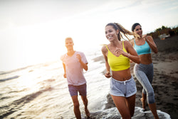 People enjoying themselves running in the sun on the beach