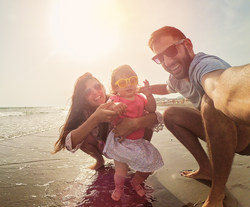 Mum and dad at the beach with their kid.