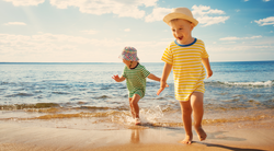 Babies running on the beach towards the camera.