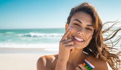 Girl holding Soléo sunscreen on a beach.